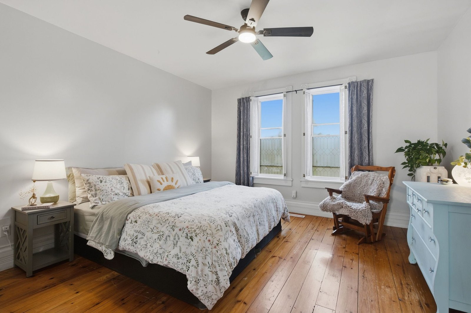 Primary bedroom with hardwood floors and tall windows