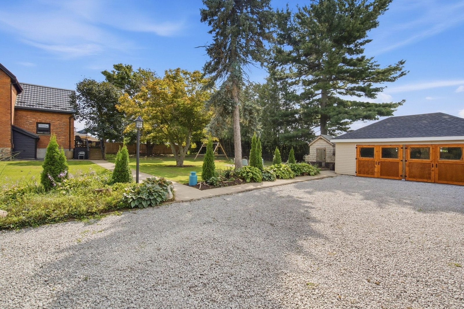 Gravel driveway leading to the garage between mature trees